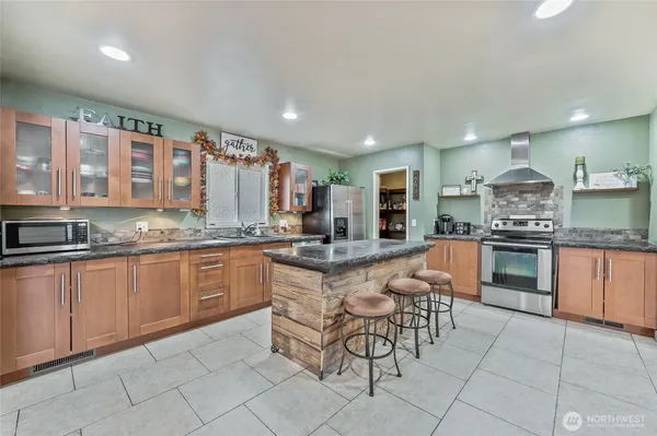 a kitchen with stainless steel appliances granite countertop table chairs sink and cabinets