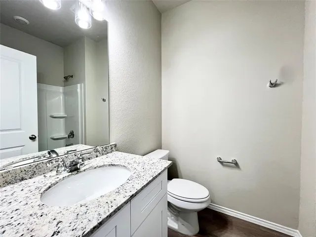 a bathroom with a granite countertop toilet and a sink