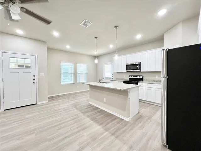 a kitchen with granite countertop white cabinets sink and stainless steel appliances