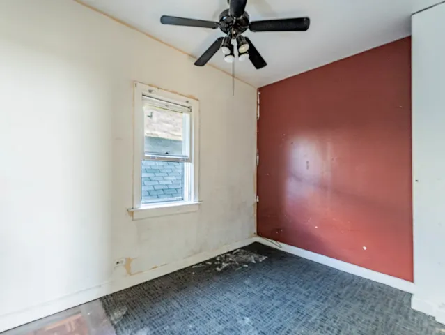 an empty room with ceiling fan and window