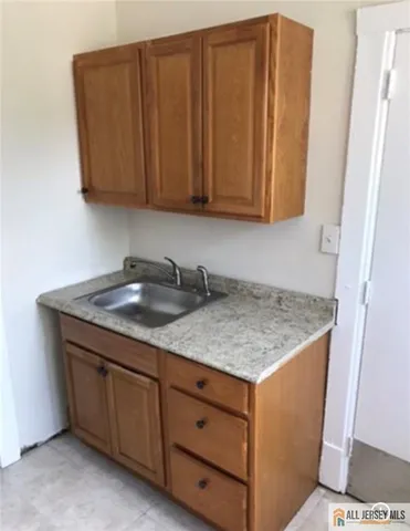 a utility room with granite countertop cabinets and sink