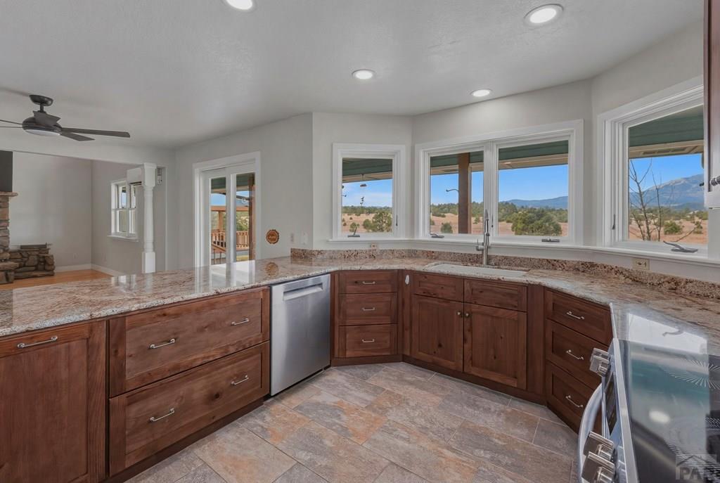 23360 Monarch Road Aguilar, CO 81020 - Photo 5 of 52 a large kitchen with granite countertop a sink and dishwasher wooden cabinets with a large window