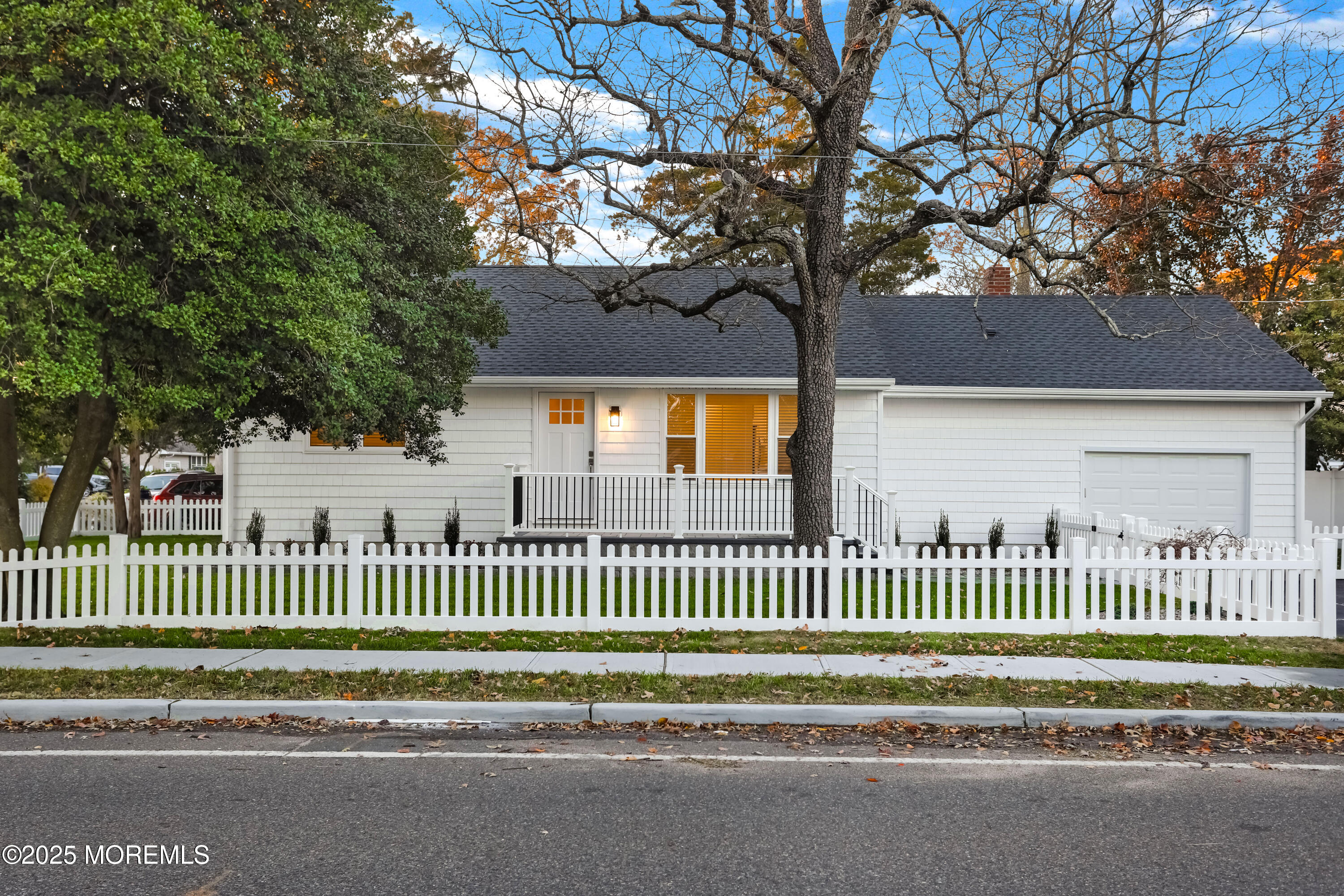 a view of a house with a small yard and a large tree