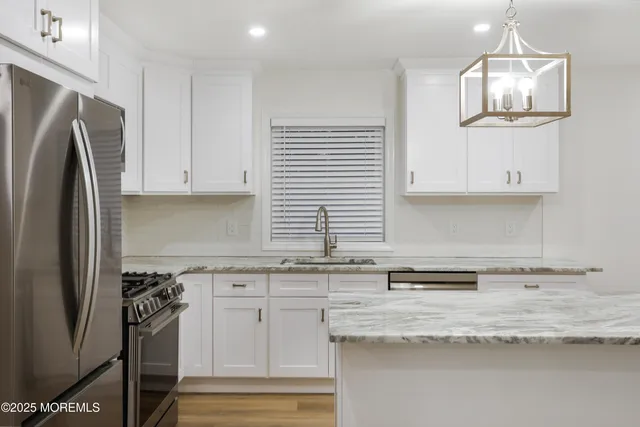 a kitchen with stainless steel appliances granite countertop a refrigerator a stove and white cabinets