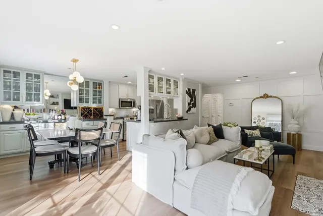 a living room with furniture and a large mirror with wooden floor