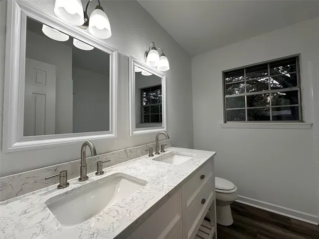 a bathroom with a granite countertop sink a toilet and a mirror