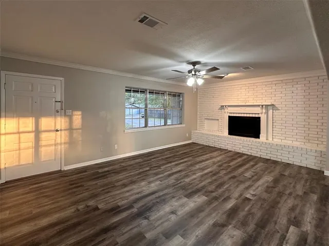 an empty room with wooden floor fireplace and windows