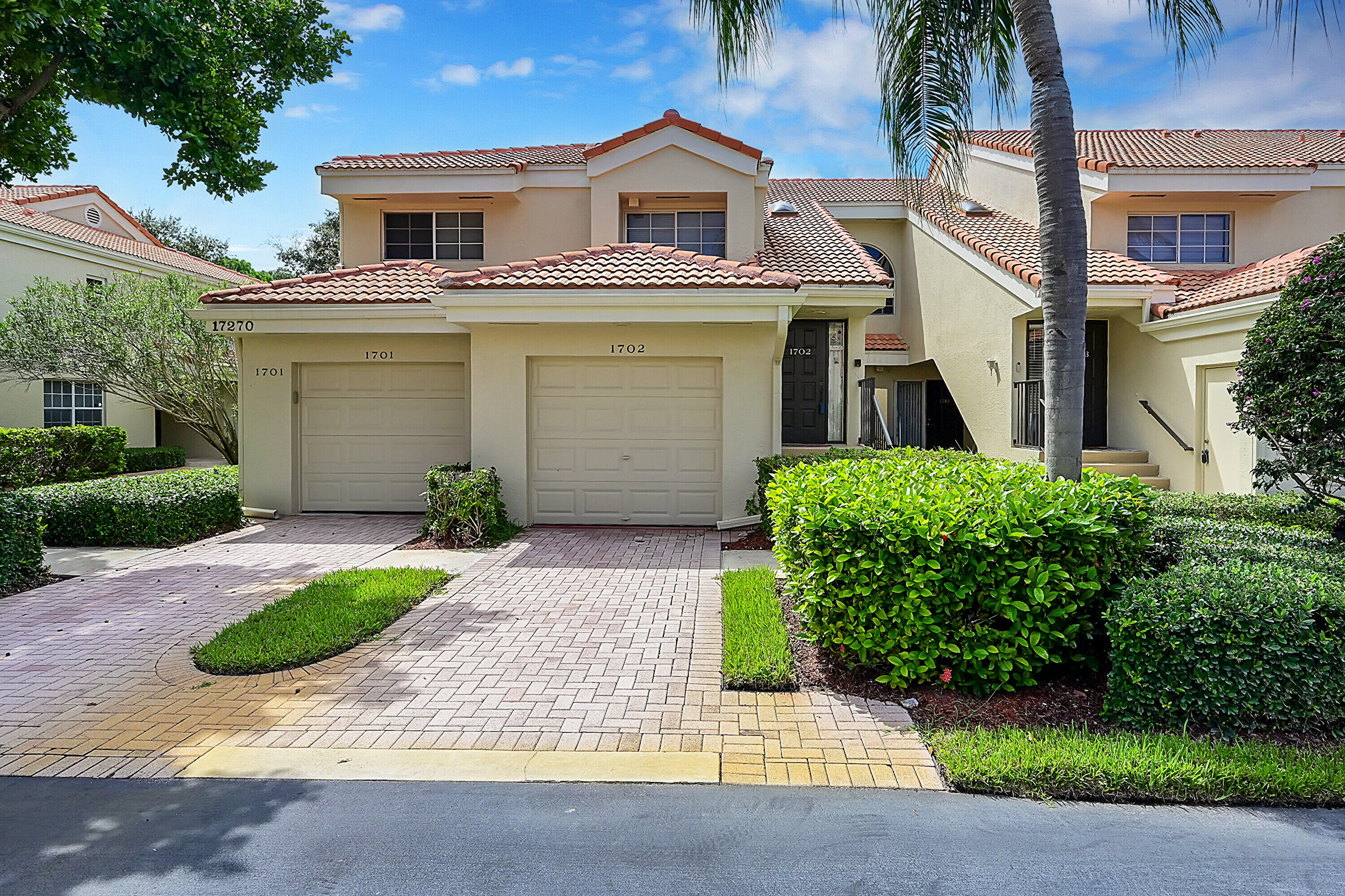 17270 Boca Club Boulevard, Unit 1702 Boca Raton, FL 33487 - Photo 1 of 41 a view of a white house with a yard plants and palm trees