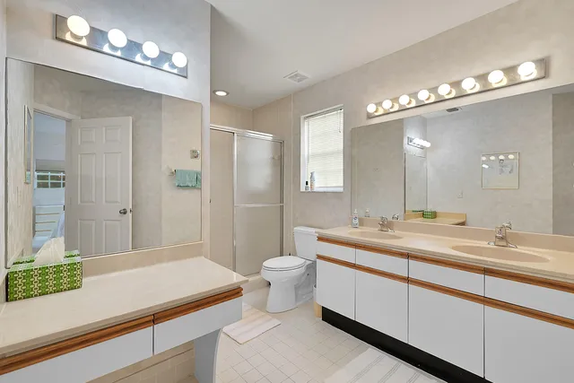 a spacious bathroom with a sink a toilet a mirror and shower