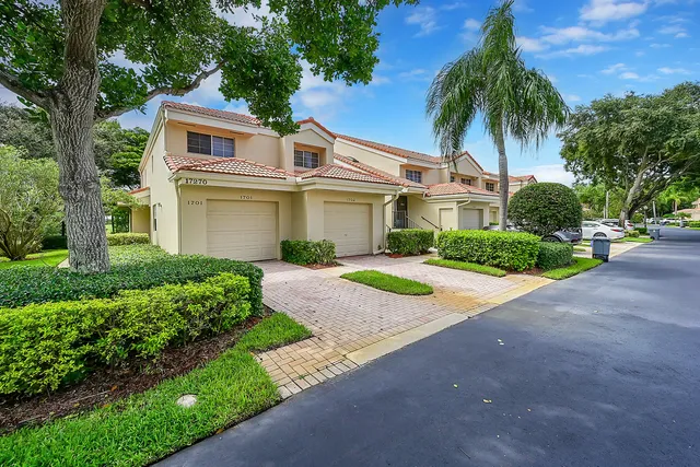 a front view of a house with a garden and palm trees