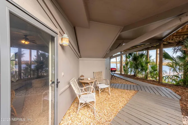 a view of a patio with table and chairs potted plants and floor to ceiling window