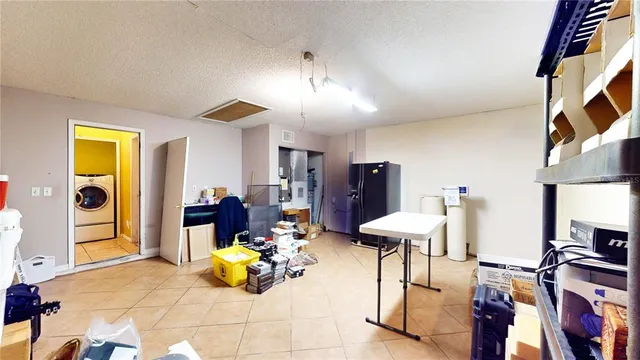 a living room with stainless steel appliances furniture a rug and a kitchen