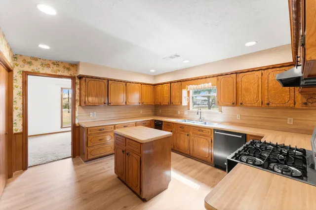a large kitchen with stainless steel appliances granite countertop a stove a sink and a refrigerator