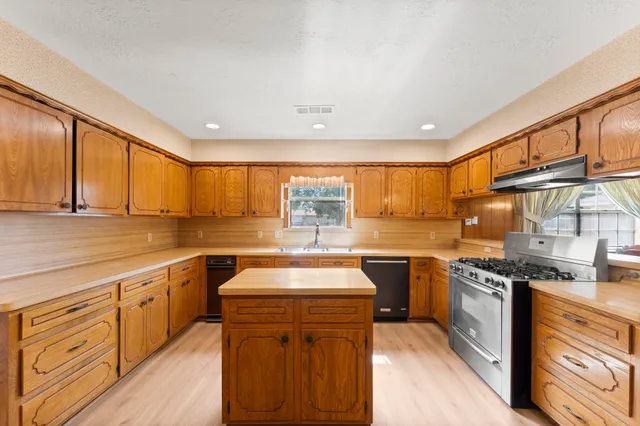 a kitchen with stainless steel appliances granite countertop a stove a sink and a refrigerator