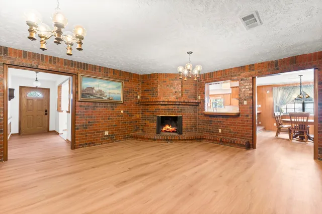 a view of an empty room with wooden floor and a fireplace