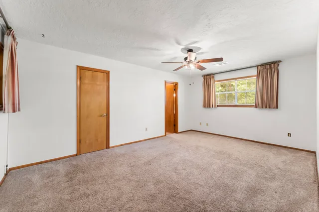 an empty room with windows and fan