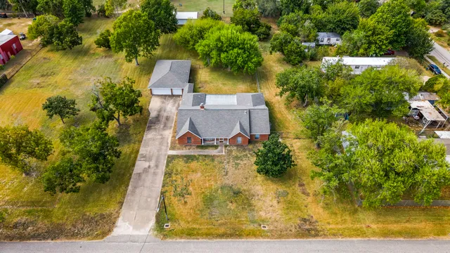an aerial view of a house with swimming pool and large trees