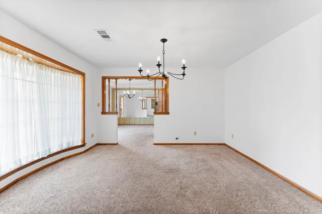 an empty room with chandelier fan and windows