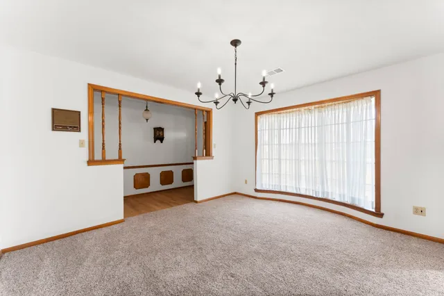 an empty room with chandelier fan and windows