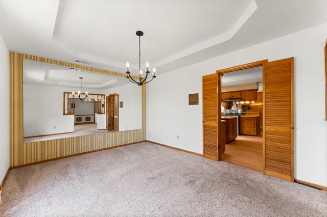 an empty room with chandelier fan and windows