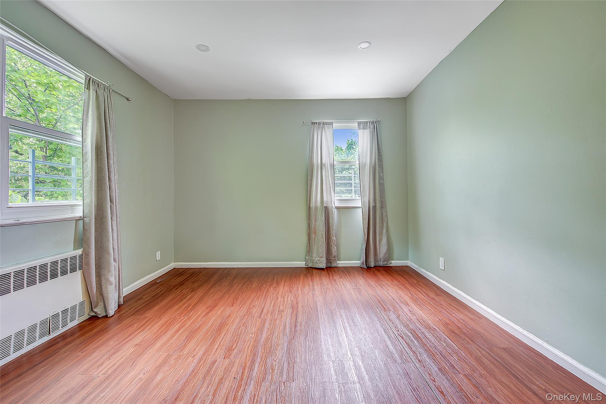 164-38 76th Road Queens, NY 11366 - Photo 16 of 44 an empty room with wooden floor and windows