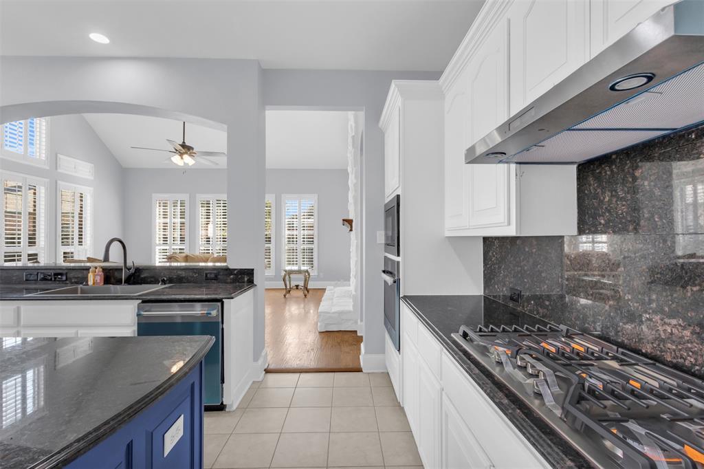 4306 Mitchell Lane Rowlett, TX 75088 - Photo 13 of 39 Kitchen with light tile patterned floors, dark stone countertops, appliances with stainless steel finishes, under cabinet range hood, and white cabinetry