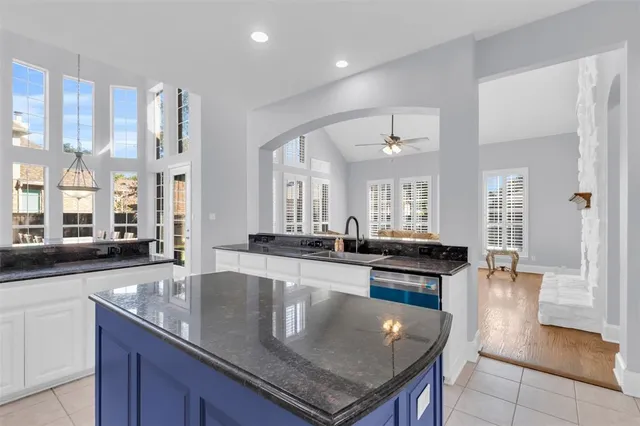 a kitchen with granite countertop stainless steel appliances a sink a counter top space and living room view