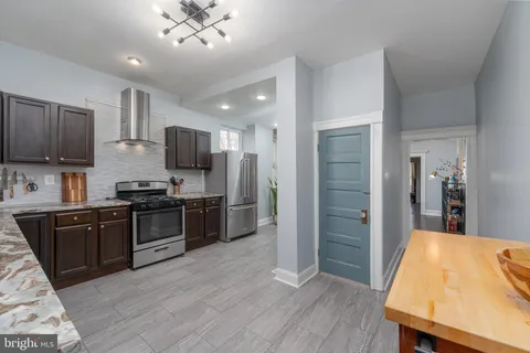 a kitchen with stainless steel appliances granite countertop wooden cabinets a refrigerator a stove a sink and dishwasher with wooden floor