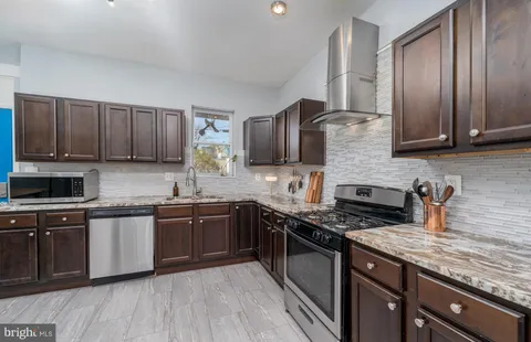 a kitchen with stainless steel appliances granite countertop wooden cabinets a stove top oven a sink and dishwasher