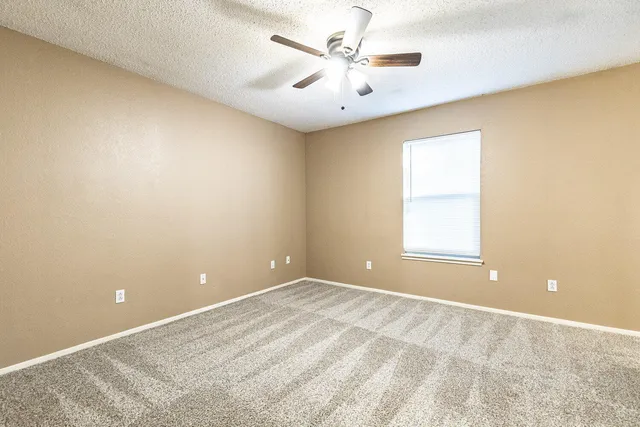 an empty room with a ceiling fan and a shower
