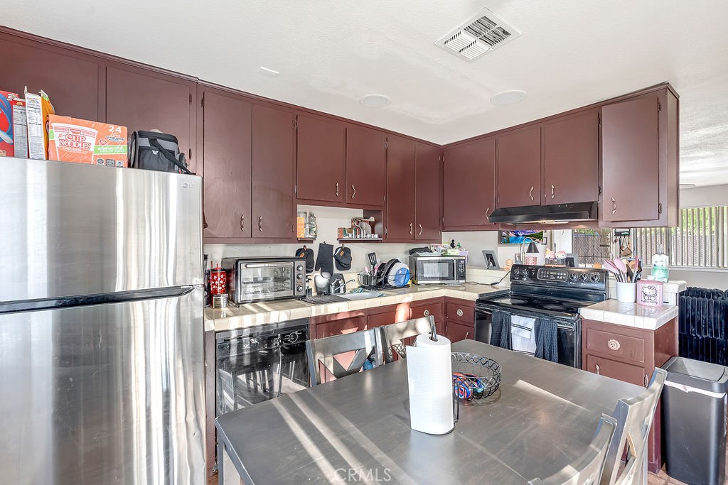 13250 Mohawk Road Apple Valley, CA 92308 - Photo 8 of 16 a kitchen with stainless steel appliances granite countertop a refrigerator a sink dishwasher a stove top oven a kitchen island and chairs with wooden floor