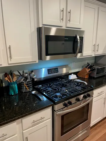 a kitchen with stainless steel appliances granite countertop a stove and a microwave