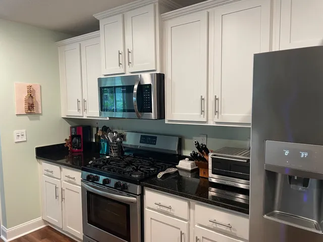 a kitchen with stainless steel appliances granite countertop white cabinets and black stove top oven with granite countertops
