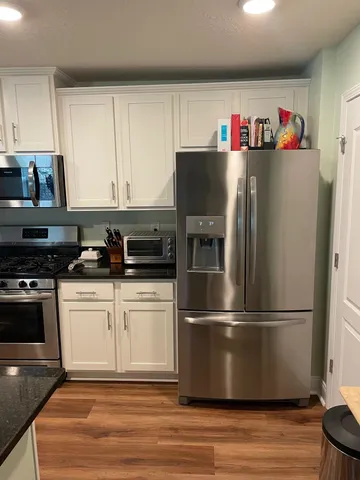a kitchen with granite countertop a refrigerator and a stove top oven