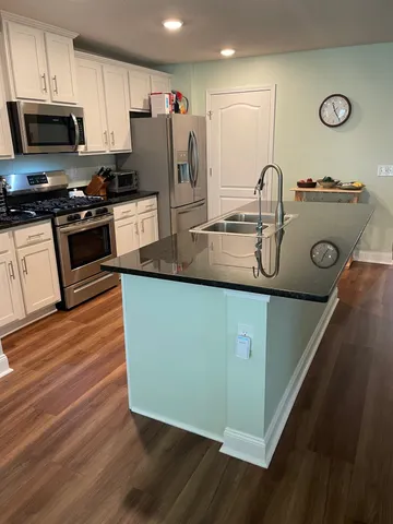 a kitchen with stainless steel appliances granite countertop a sink a stove and a refrigerator