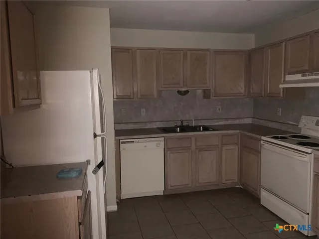 a kitchen with a refrigerator and white cabinets