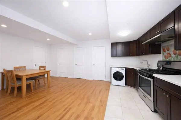 a kitchen with stainless steel appliances granite countertop a stove top oven a sink dishwasher and a refrigerator with wooden floor