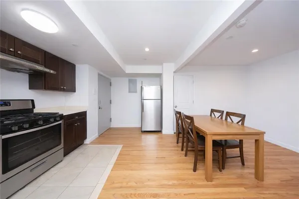 a kitchen with stainless steel appliances kitchen island granite countertop a table chairs sink and cabinets