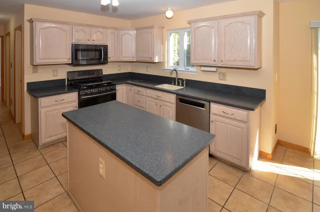 a kitchen with granite countertop a sink a stove top oven and cabinets