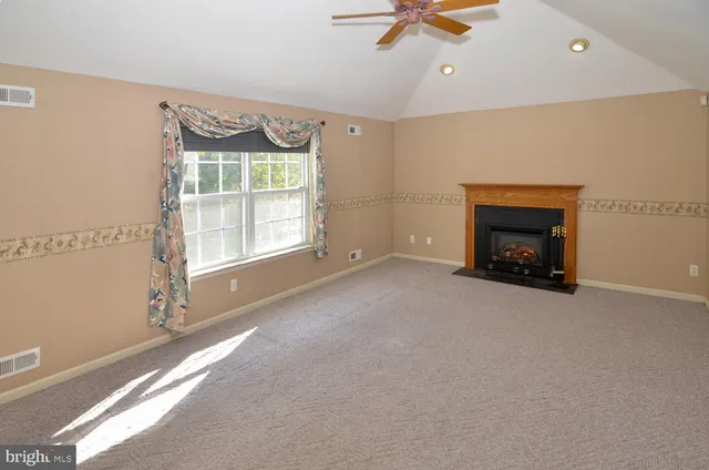 a view of an empty room with a fireplace and a window