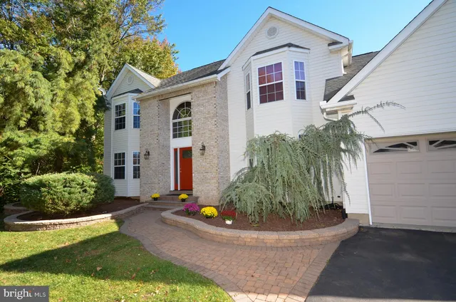 a view of a white house next to a yard with potted plants