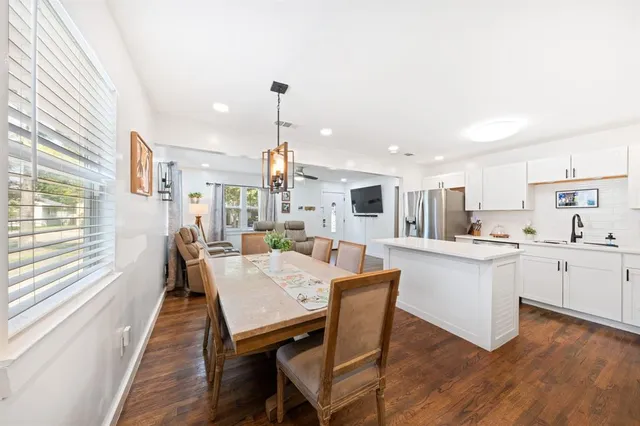 a kitchen with stainless steel appliances kitchen island granite countertop a table chairs sink and cabinets