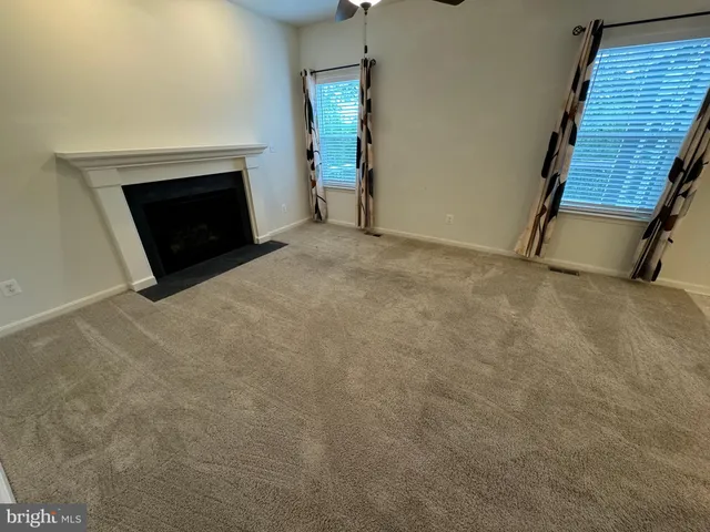 a view of an empty room with wooden floor and a fireplace