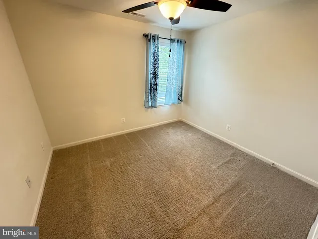 an empty room with a window and a chandelier fan