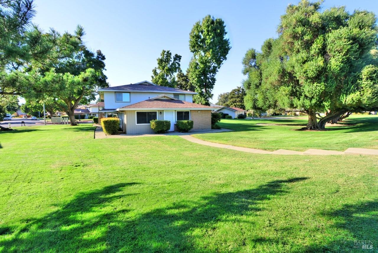 a front view of a house with garden and trees