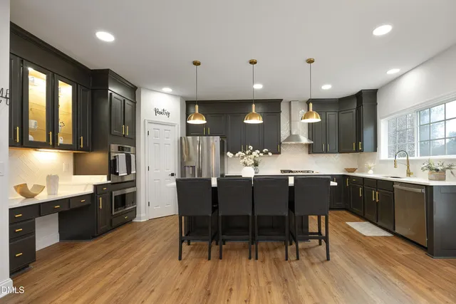 a kitchen with stainless steel appliances kitchen island granite countertop a stove a sink a refrigerator dining table and chairs