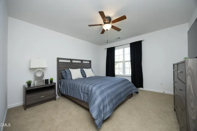a bedroom with a bed painting on wall and windows