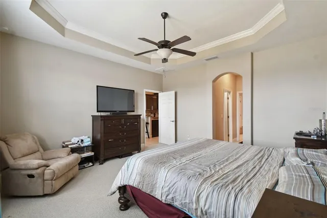 a bedroom with a bed a dresser and a chandelier