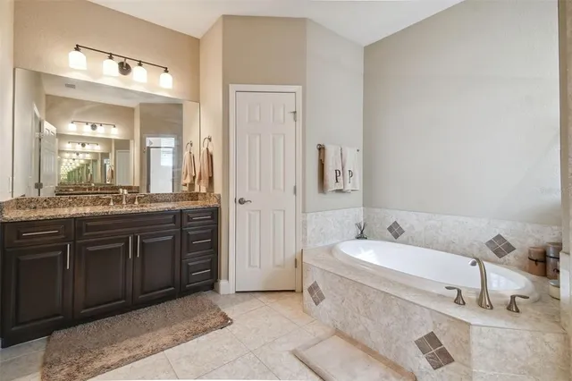 a spacious bathroom with a tub sink and mirror