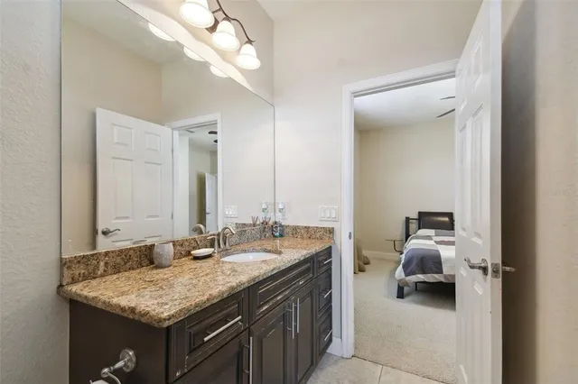 a en suite bathroom with a granite countertop sink and a mirror